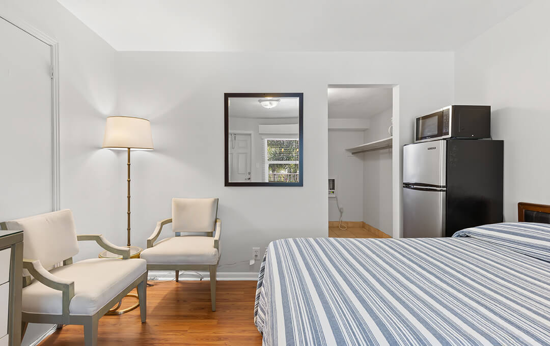 A fullshot of a Basic Motel Bed Room with refrigerator.