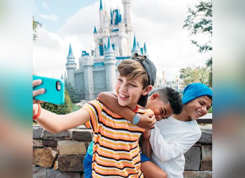 A full shot of a group of children taking a photo with a castle in the background.